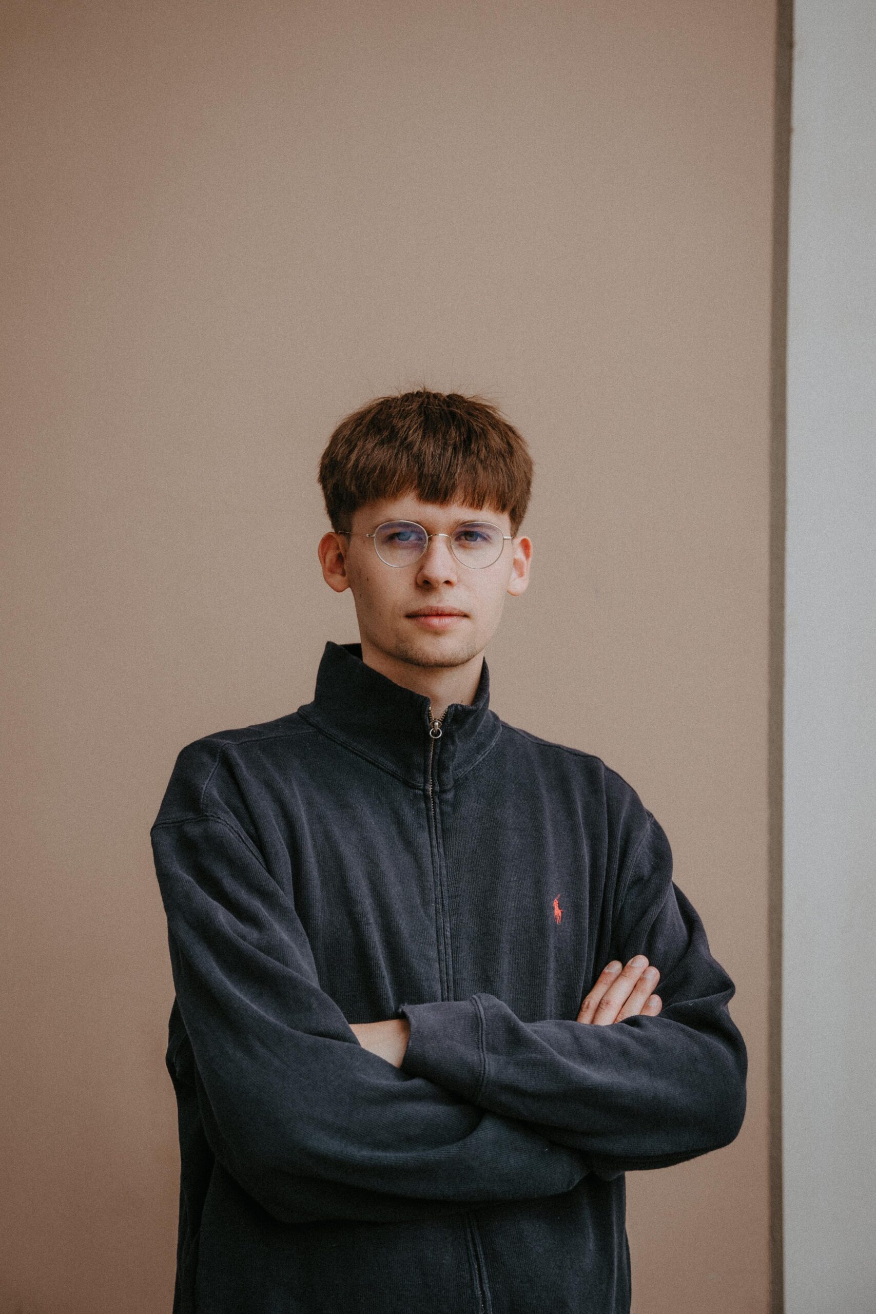 Jakob Springfeld mit verschränkten Armen vor einer Wand.